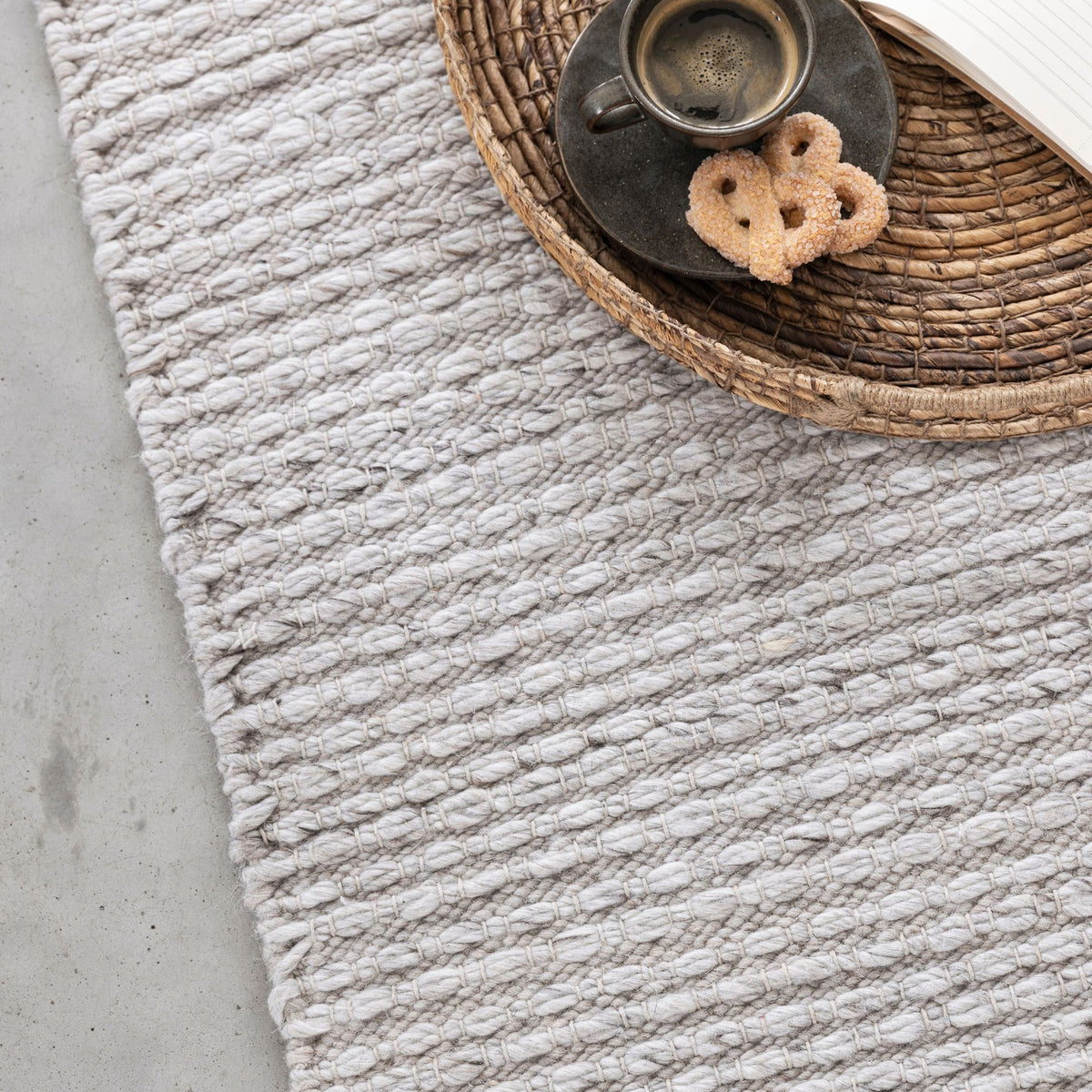 Het ronde Nirvana vloerkleed van MUST Living in grijs gestyled in een woonkamer