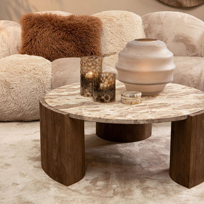 Curvae Sofa Lush Beige van PTMD achter een ronde salontafel met vazen en een bruin sierkussen
