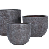 Delsey Brown GRC Structure Pot Big Set Of 3 van PTMD, set van drie bruine potten met structuur in een sfeervolle buitensetting