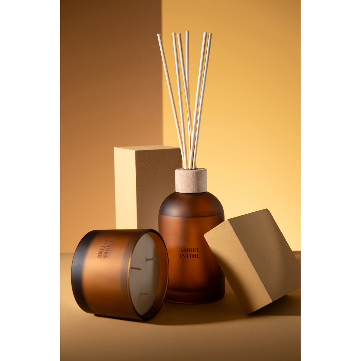 Geurstokjes Accords Essentiels Ambre Intime 550ml van J-Line samen met bijpassende geurkaars uit de Ambre Intime lijn