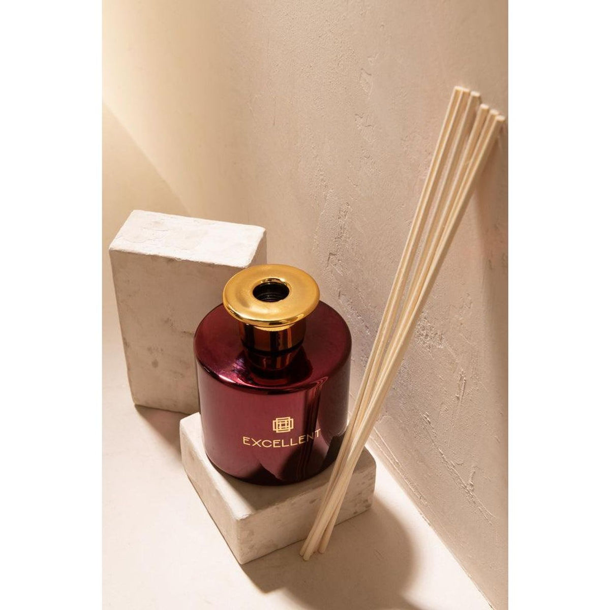 Close-up van de wijnrode geurstokjesfles met rieten stokjes op een betonnen blok