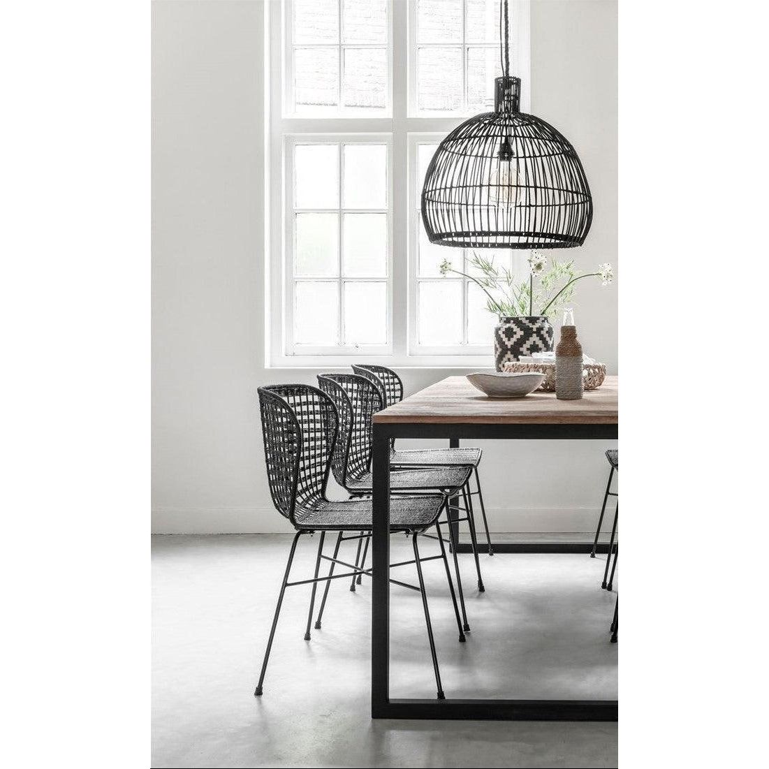 Hanglamp Las Salinas Large van MUST Living, grote zwarte pitrieten kap boven een houten eettafel