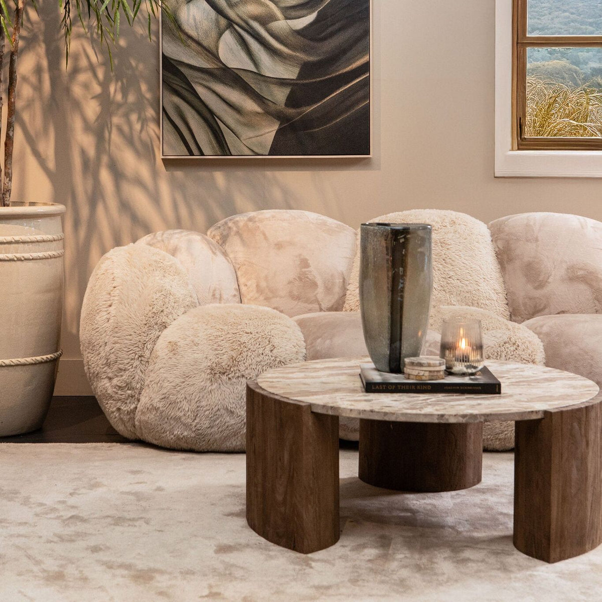 Javina salontafel van PTMD in een lichte woonkamer naast een ronde bank en plant