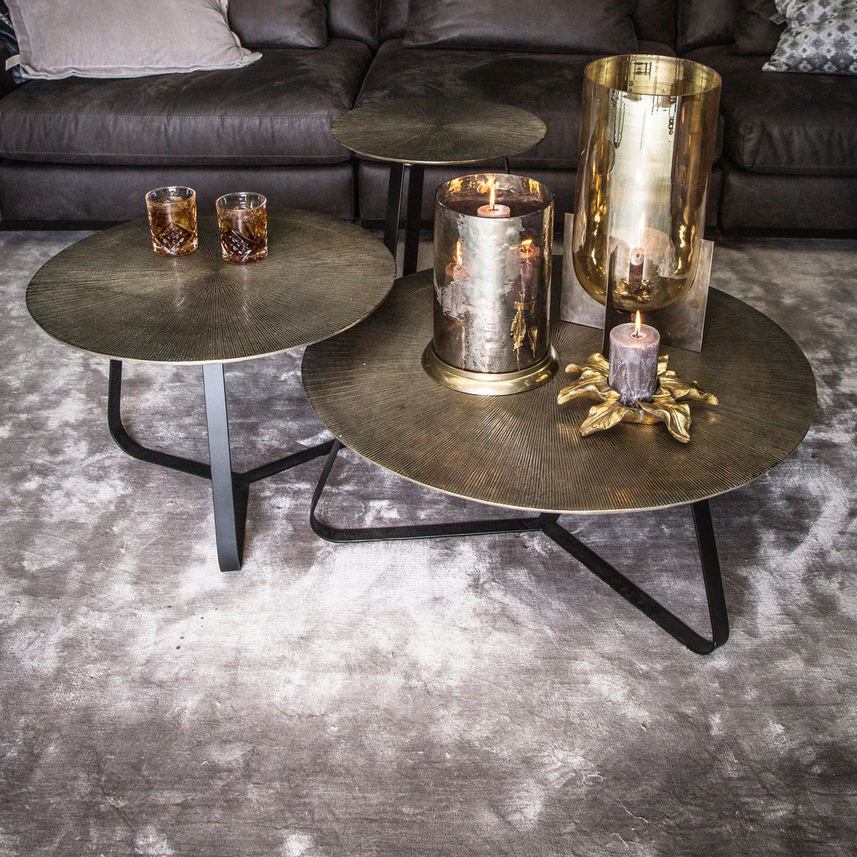 Kae bijzettafels van PTMD met goud aluminium blad op een hoogpolig vloerkleed, gestyled met gouden vazen