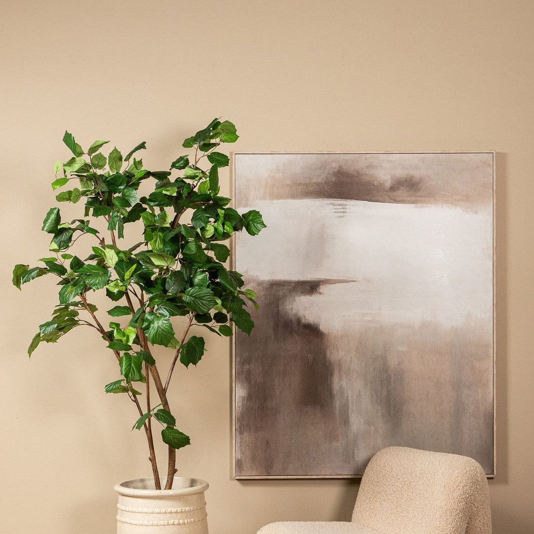 Kunstboom met druivenbladeren van PTMD in een woonkamer naast een fauteuil