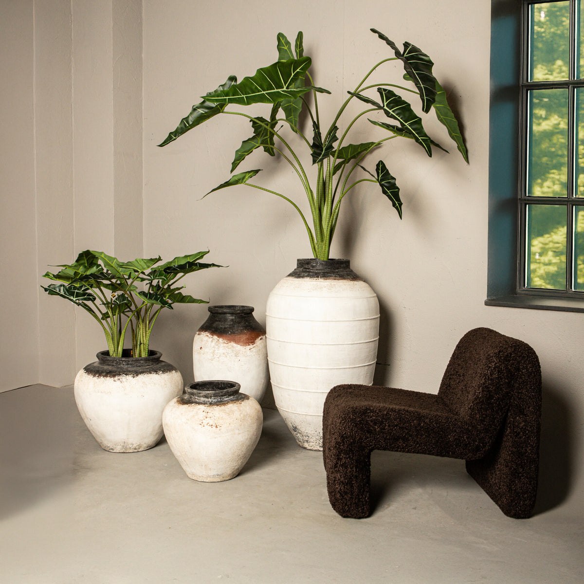 Bruine Oslo teddy fauteuil van PTMD in een lichte kamer met grote vazen en planten
