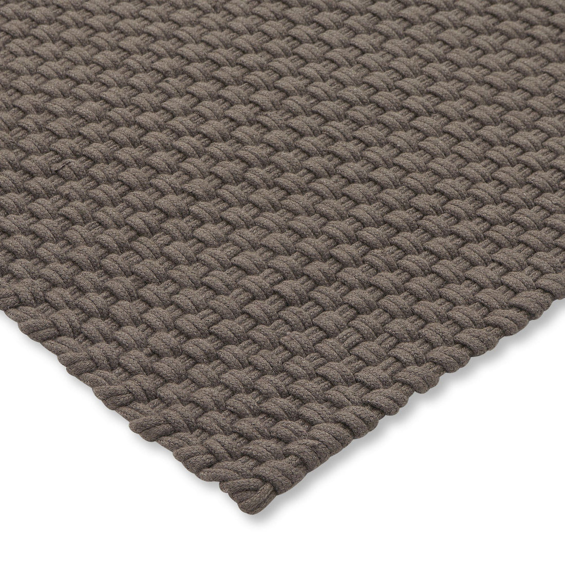 Het grote Nomad tapijt in Grey Taupe onder een buitenbank en fauteuils