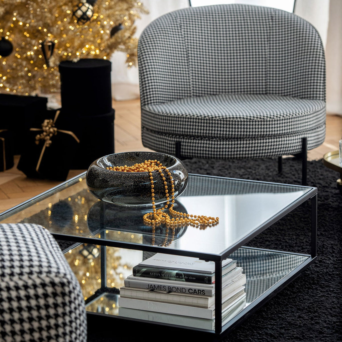 Sierschaal Carol Large van J-Line, zwarte glazen schaal met gouden kralen op een glazen salontafel