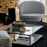 Sierschaal Carol Large van J-Line, zwarte glazen schaal met gouden kralen op een glazen salontafel