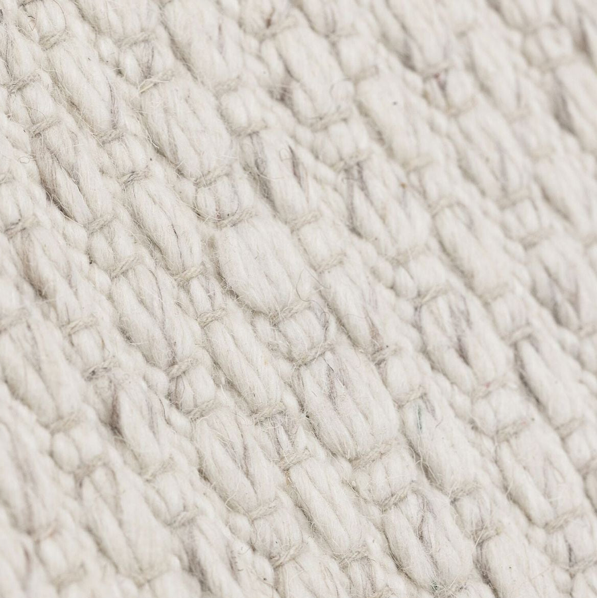 Vloerkleed Nirvana van MUST Living, detailfoto van de dikke gevlochten wolstructuur in ivoor