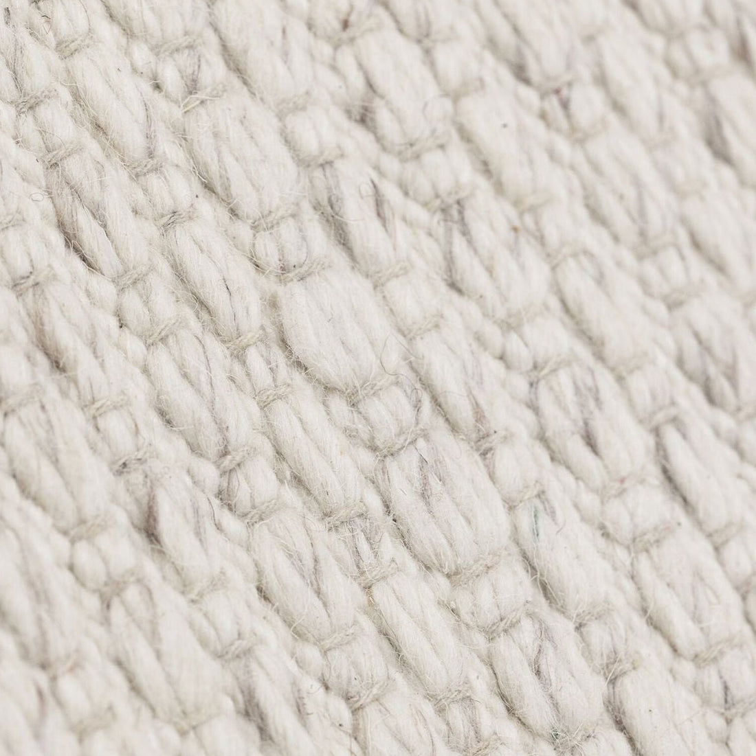 Vloerkleed Nirvana van MUST Living, detailfoto van de dikke gevlochten wolstructuur in ivoor