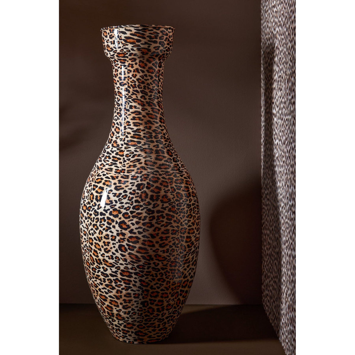 Vloervaas Leo van J-Line in een woonkamer, metalen vaas met panterprint naast een zithoek