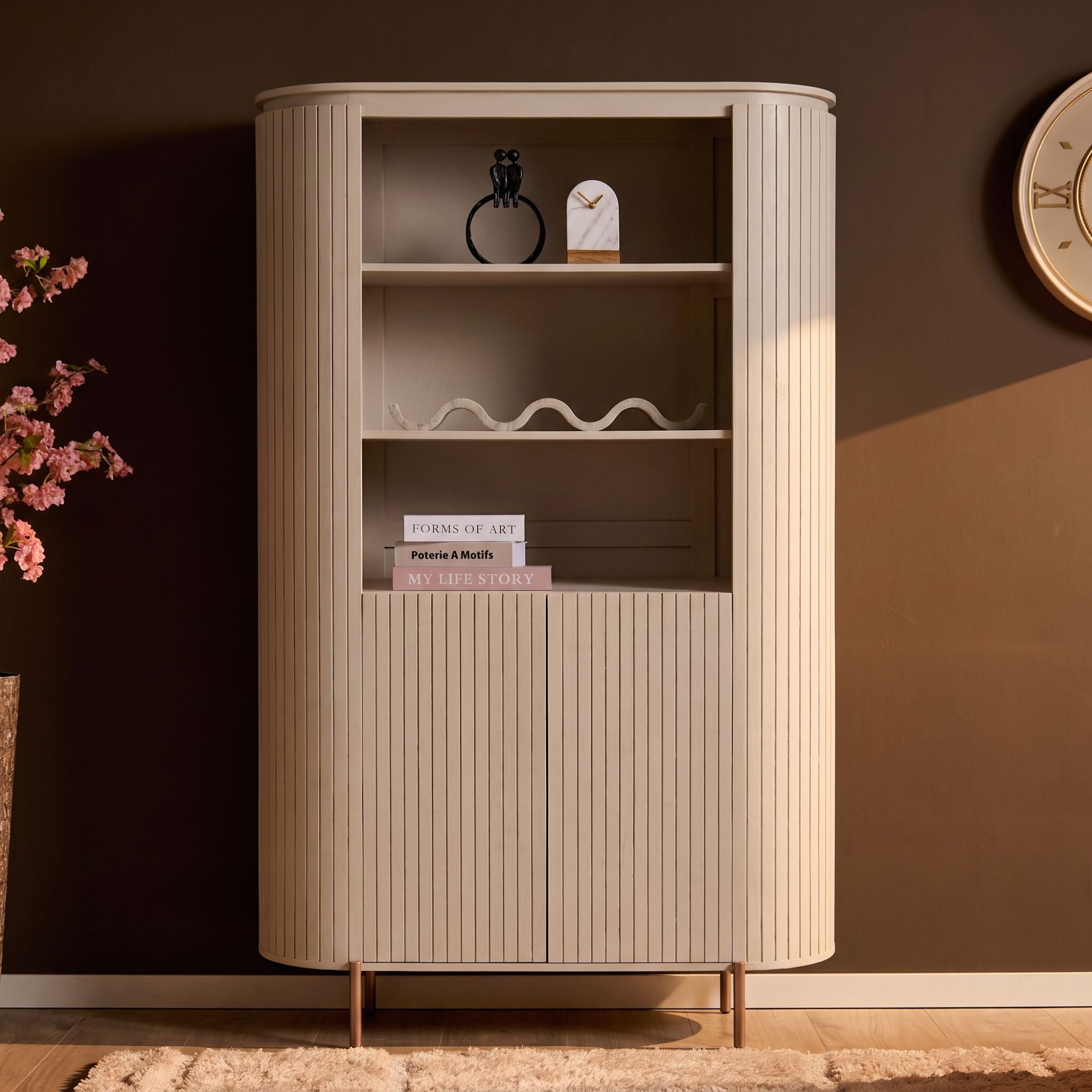 Zandkleurige Solana wandkast gestyled met boeken en vazen in de woonkamer