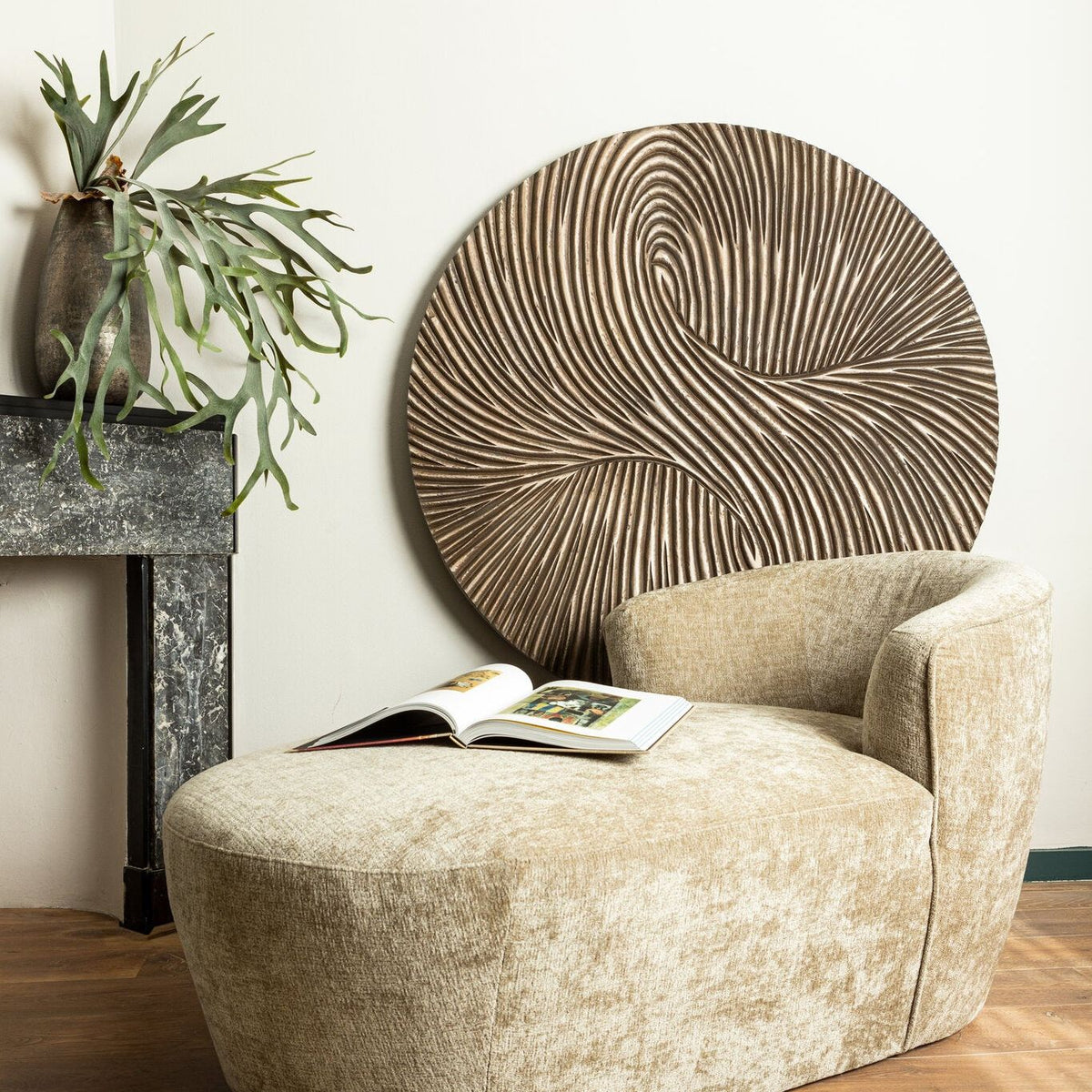 Wandpaneel Wiktor Rond Bruin Ø120cm van PTMD in een lichte woonkamer met beige fauteuil en hocker