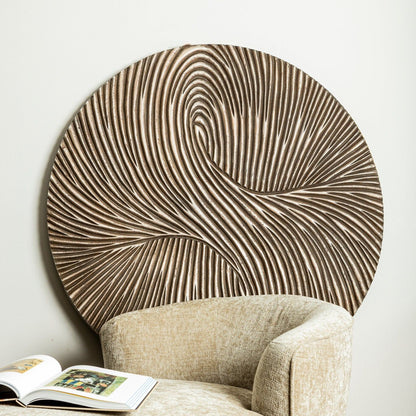 Wandpaneel Wiktor Rond Bruin Ø120cm van PTMD achter een beige fauteuil met opengeslagen boek